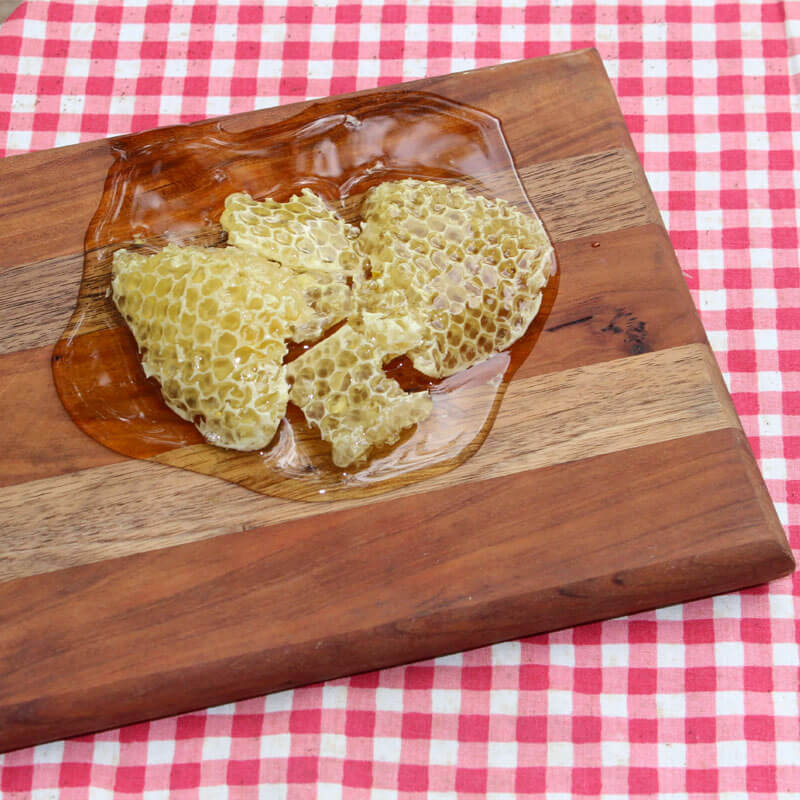 Honeycomb dripping honey on wood