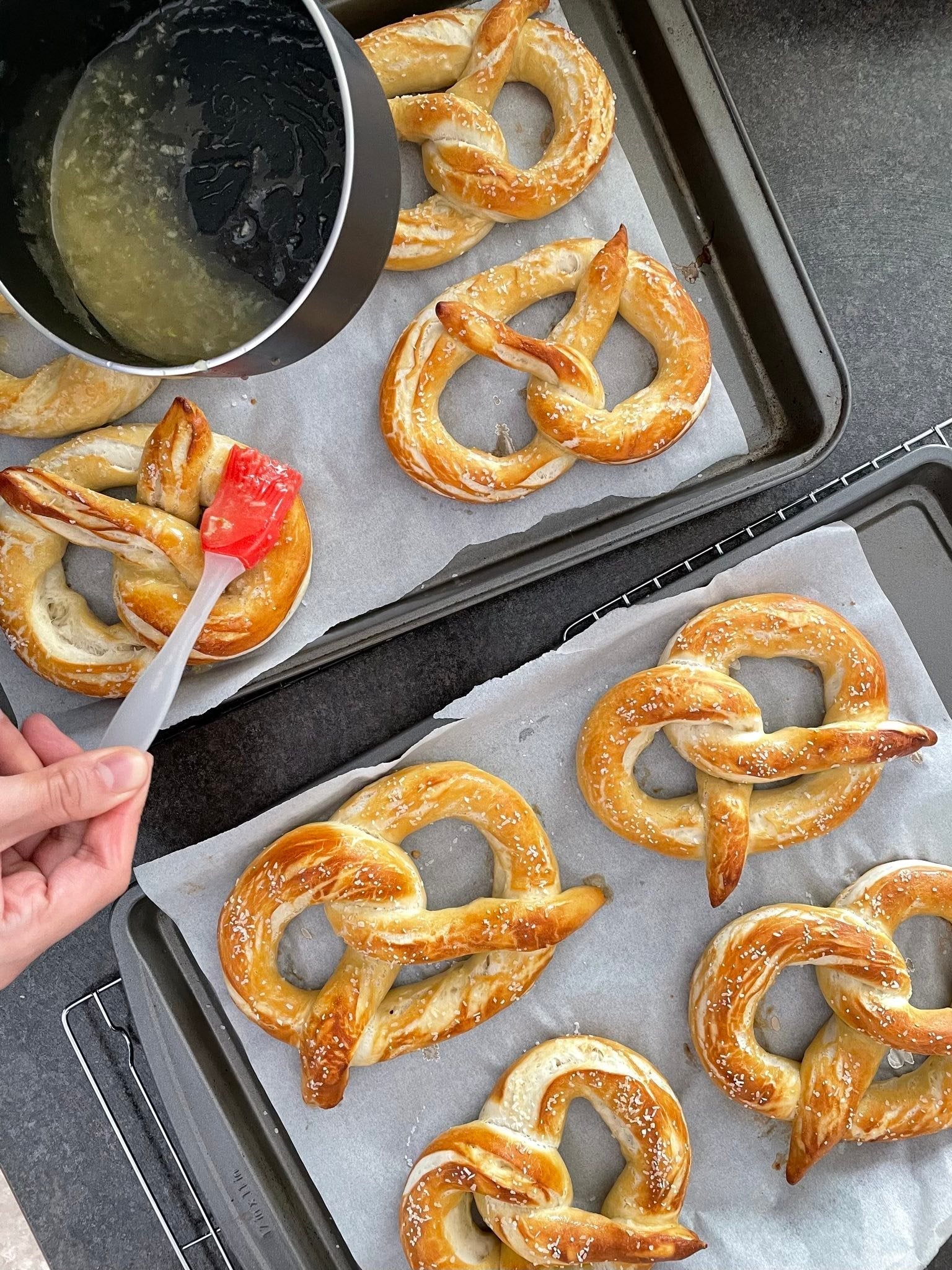 Freshly baked pretzels being brushed with egg wash
